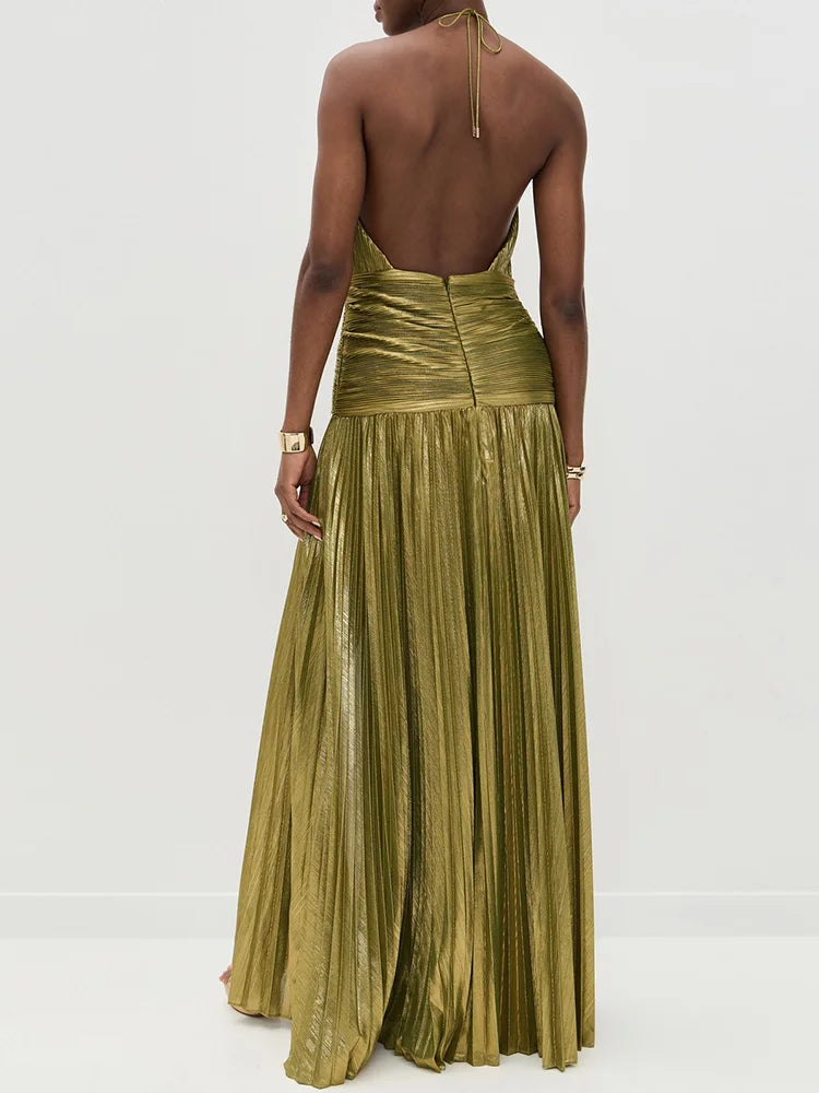 Back view of model wearing gold pleated halter maxi dress showing zipper closure and how the dress flows from behind